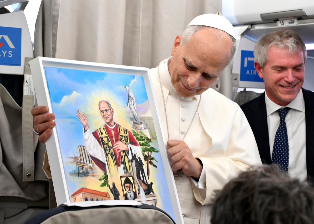 Pope Leo XIV shows a gift he received as he talks to reporters aboard an airplane as he returns from a six-day visit to Turkey and Lebanon, Tuesday, Dec. 2, 2025. (Alessandro Di Meo/Pool Photo via AP)