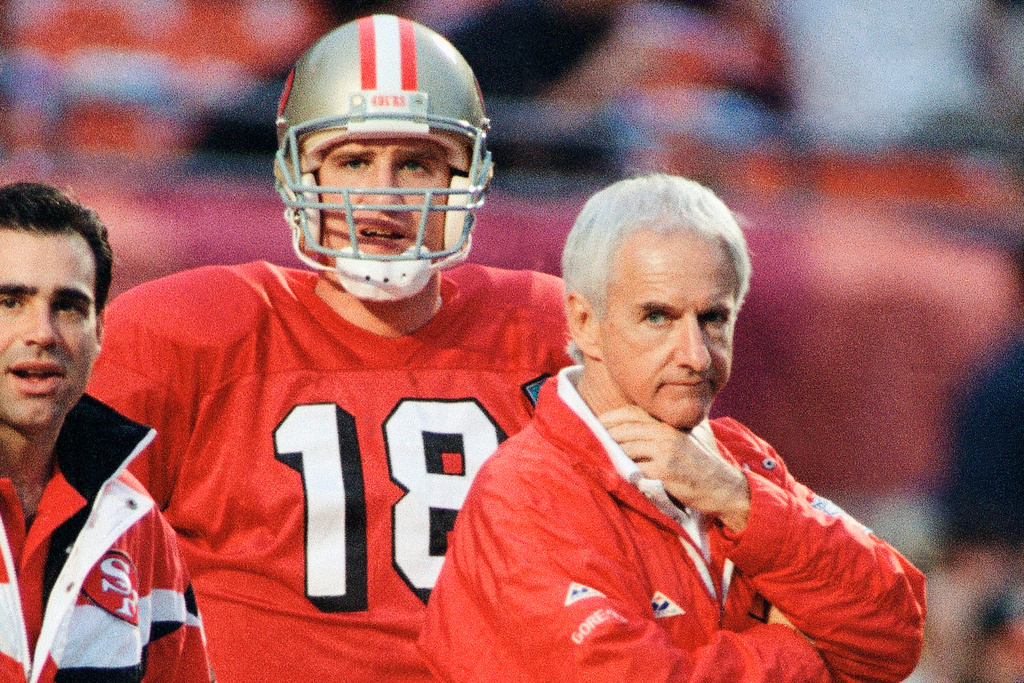FILE - San Francisco 49ers coach George Seifert, right, and backup quarterback Elvis Grbac watch pre-game warm-ups at Miami's Joe Robbie Stadium, Jan. 29, 1995, before facine the San Diego Chargers today in the NFL Super Bowl Super Bowl XXIX football game. (AP Photo/Doug Mills, File)