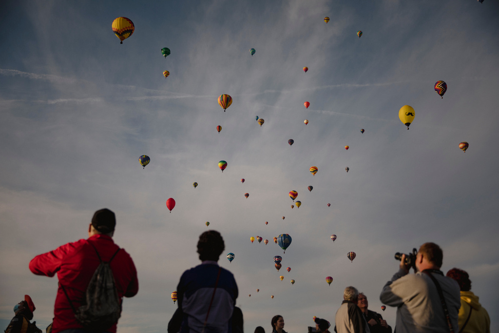 FILE - A crowd watches as hundreds of hot air balloons fill the morning sky over Albuquerque, N.M., on the second day of the Balloon Fiesta Oct. 3, 2021. (Adria Malcolm/The Albuquerque Journal via AP, File)