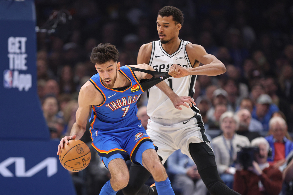 San Antonio Spurs forward Victor Wembanyama (1) holds the shirt of Oklahoma City Thunder center Chet Holmgren (7) during the first half of an NBA basketball game Tuesday, Jan. 13, 2026, in Oklahoma City. (AP Photo/Nate Billings)