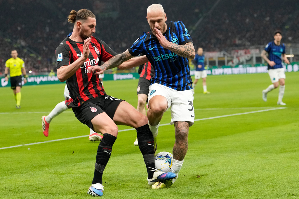 Inter Milan's Federico Dimarco, centre right, and AC Milan's Adrien Rabiot challenge for the ball during the Serie A soccer match between AC Milan and Inter Milan, in Milan, Italy, Sunday, March 8, 2026. (AP Photo/Luca Bruno)