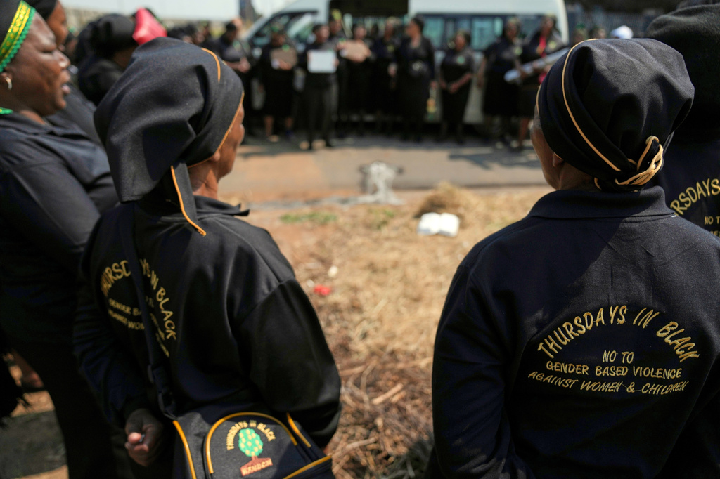 A women's church group pay their respect at a scene of a discovery of the body of a 38-year-old woman last week while jogging, in Kempton Park, east of Johannesburg, South Africa, Thursday, Sept. 17, 2026. (AP Photo/Themba Hadebe)