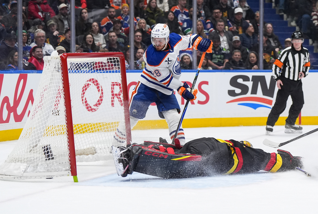 Edmonton Oilers' Jack Roslovic (28) scores against Vancouver Canucks goalie Nikita Tolopilo, bottom right, during the second period of an NHL hockey game in Vancouver, British Columbia, Saturday, Jan. 17, 2026. (Darryl Dyck/The Canadian Press via AP)
