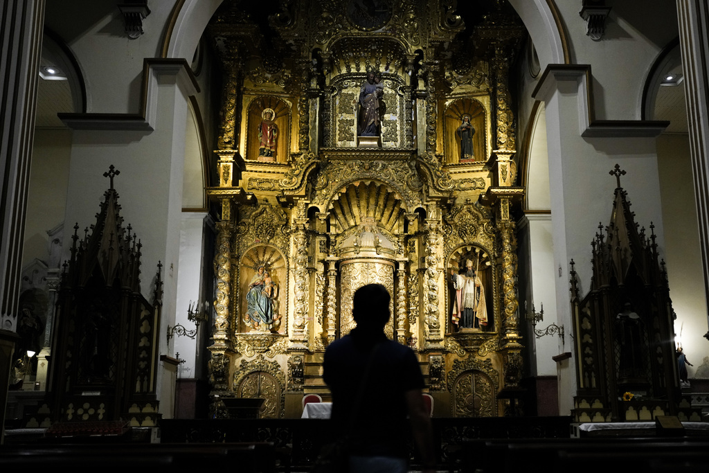 A tourist stands at the Golden Altar inside Saint Joseph Church, a baroque piece covered in gold leaf built in the 17th century after Panama City was relocated from its first settlement destroyed by pirates, in "Casco Viejo," the historic district of Panama City, Friday, Aug. 15, 2025. (AP Photo/Matias Delacroix)