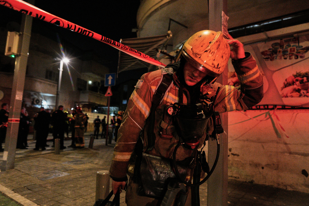An Israeli first responder walks from the site of a missile strike in Tel Aviv, Israel, early Saturday, March 28, 2026. (AP Photo/Maya Levin)