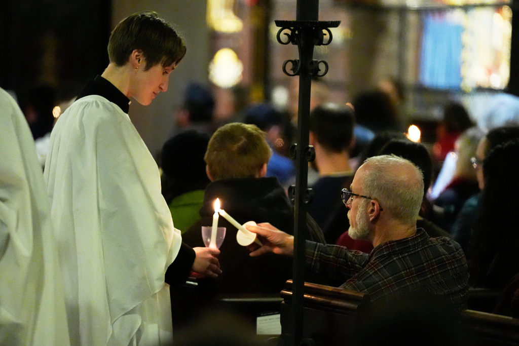Participants light candles at St. Stephen's Church during a community service for the victims of the Brown University shooting, Tuesday, Dec. 16, 2025. (AP Photo/Robert F. Bukaty)
