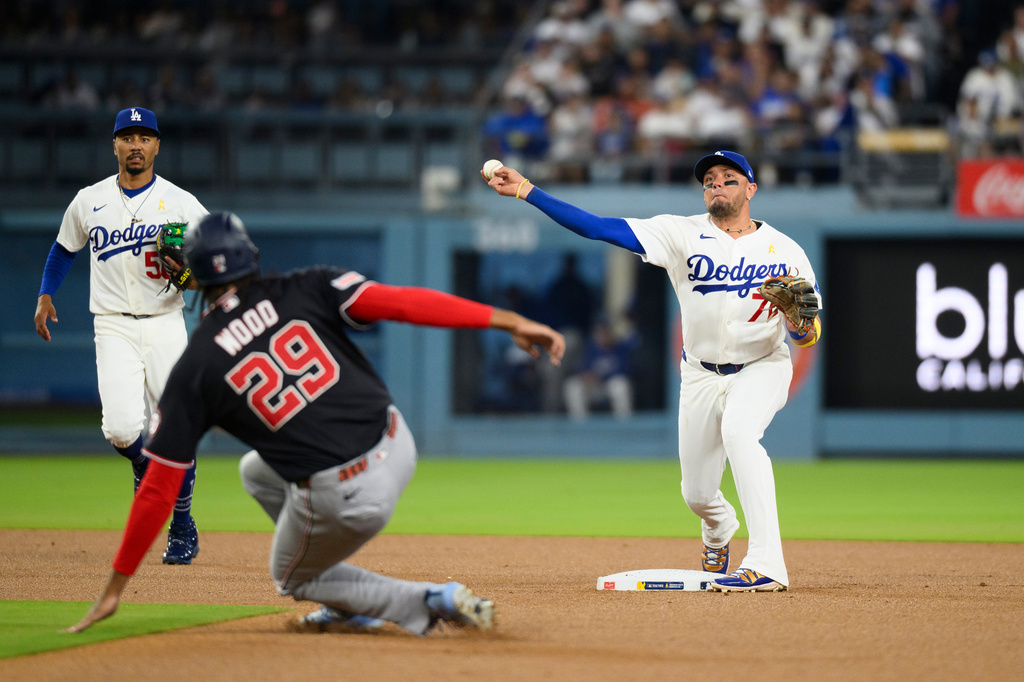 Los Angeles Dodgers second baseman Miguel Rojas (72) turns a double play over the slide by Washington Nationals' James Wood during the first inning of a baseball game in Los Angeles, Sunday, Sept. 6, 2026. Dylan Crews was out at first. (AP Photo/Kyusung Gong)