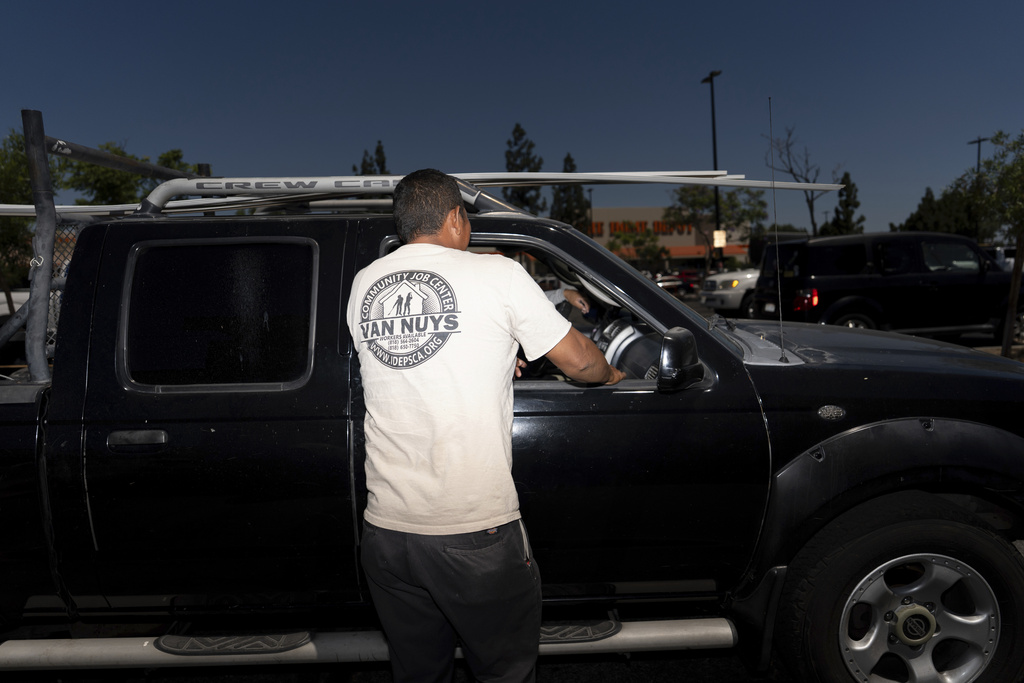 A day laborer talks to a potential client in the parking lot of a Home Depot in Los Angeles, which was targeted in ICE raids, Friday, July 25, 2025. (AP Photo/Jae C. Hong)
