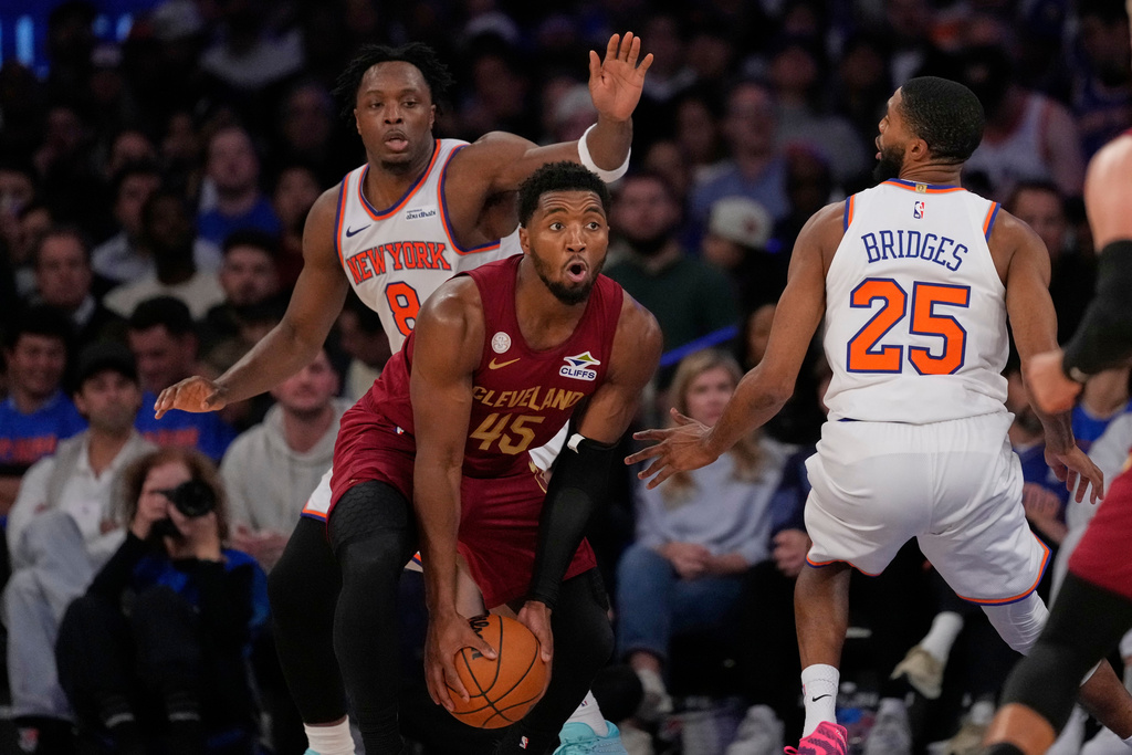 Cleveland Cavaliers' Donovan Mitchell (45) protects the ball from New York Knicks' Og Anunoby (8) and Mikal Bridges (25) during the second half of an NBA basketball game Wednesday, Oct. 22, 2025, at Madison Square Garden in New York. (AP Photo/Frank Franklin II)