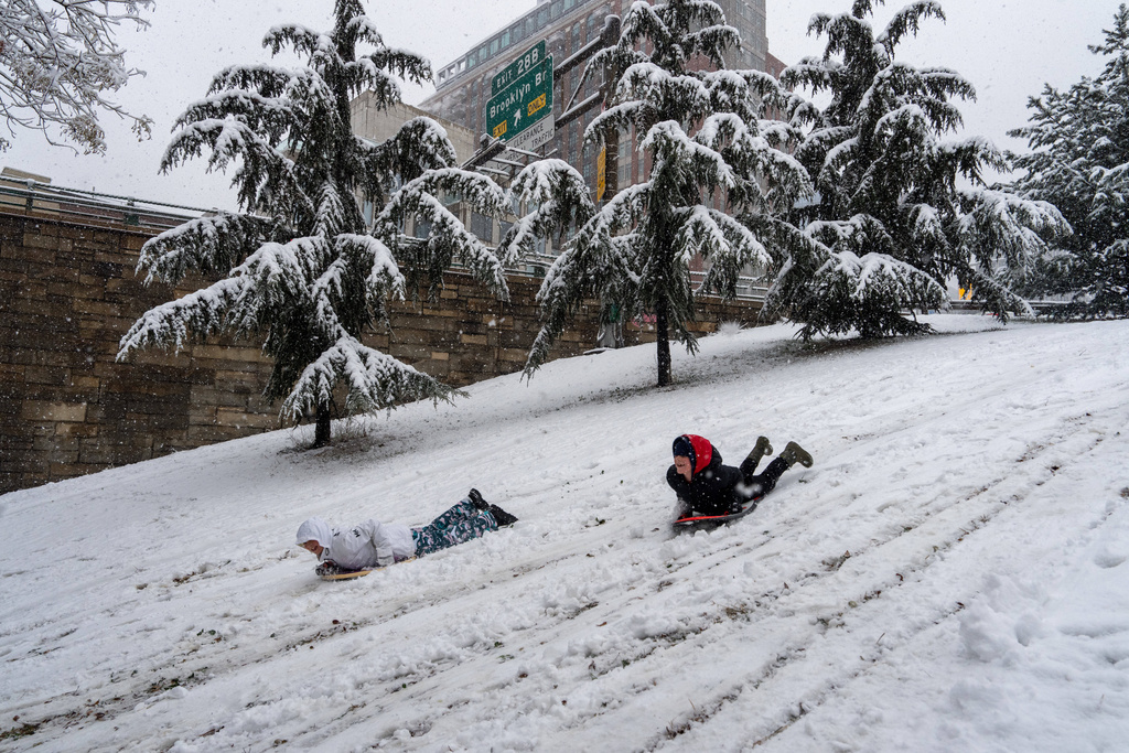 Two people sled in the snow next to the Brooklyn-Queens Expressway, Sunday, Dec. 14, 2025, in the Brooklyn borough of New York. (AP Photo/Adam Gray)