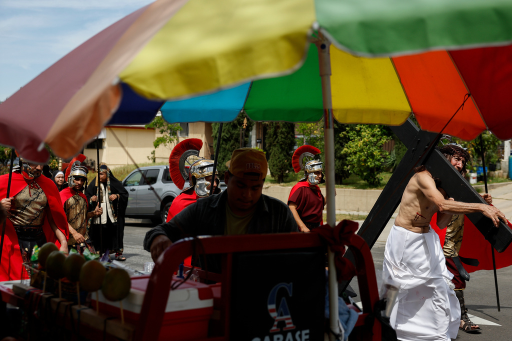 Members of the Resurrection Church walk by a street vendor as they perform during The Stations of the Cross procession through the Boyle Heights neighborhood on Good Friday, April 3, 2026, in Los Angeles. (AP Photo/Caroline Brehman)