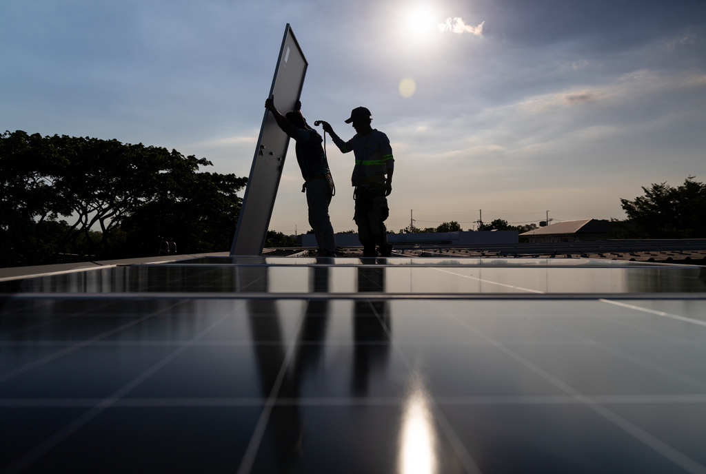 A pair of solar installers haul a solar panel onto the roof of a home in Manila, Philippines, on April 30, 2026. (AP Photo/Anton L. Delgado)
