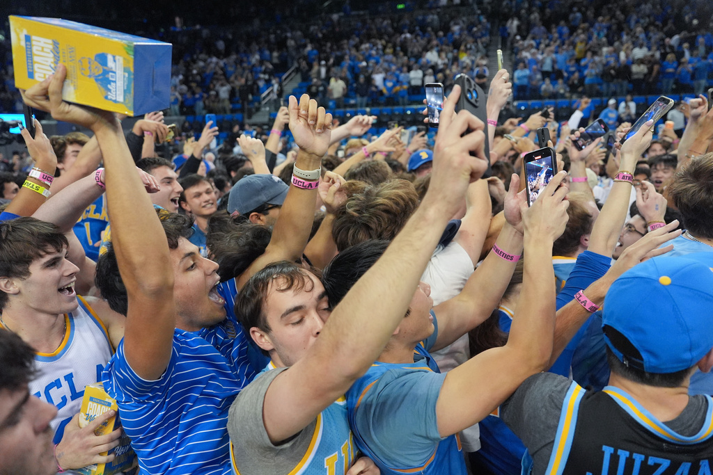 UCLA fans storm the court after the team defeated Purdue in an NCAA college basketball game in Los Angeles, Tuesday, Jan. 20, 2026. (AP Photo/Jae C. Hong)