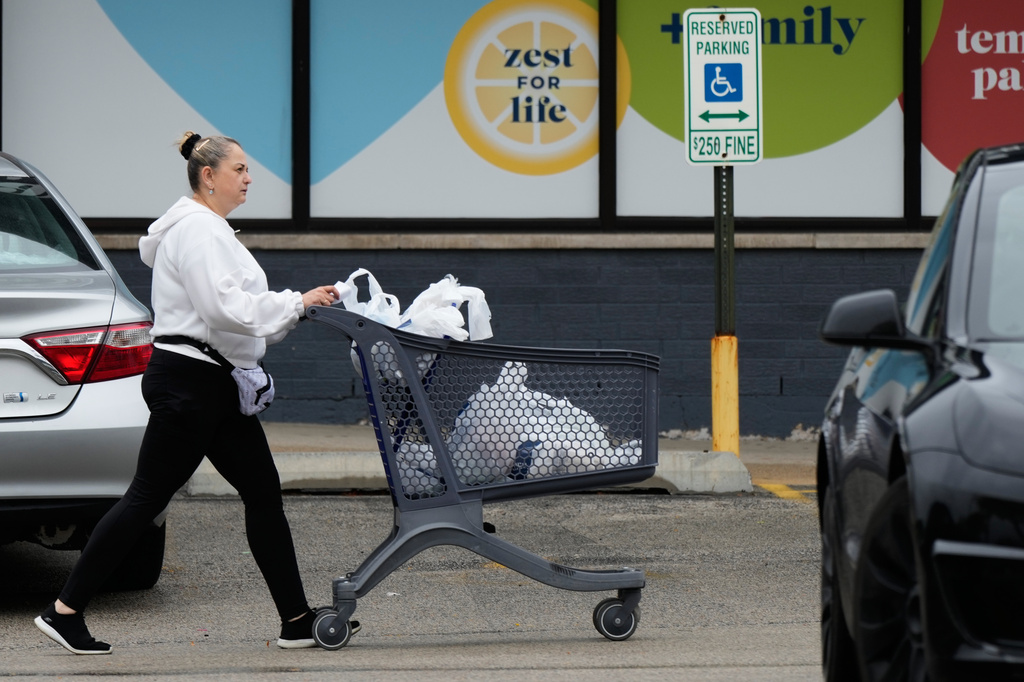 A woman pushes a shopping cart as she leaves a grocery store in Arlington Heights, Ill., Wednesday, Sept. 30, 2026. (AP Photo/Nam Y. Huh)