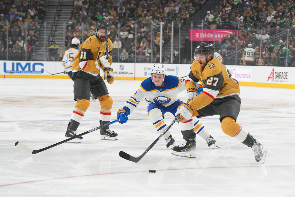 Vegas Golden Knights defenseman Shea Theodore (27) skates with the puck against Buffalo Sabres left wing Zach Benson (6) during the first period of an NHL hockey game Tuesday, March 17, 2026, in Las Vegas. (AP Photo/Candice Ward)