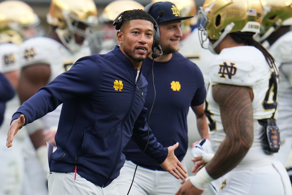 Notre Dame head coach Marcus Freeman, left, greets players as they return to the sideline during the second half of an NCAA college football game against Pittsburgh in Pittsburgh, Saturday, Nov. 15, 2025. (AP Photo/Gene J. Puskar)