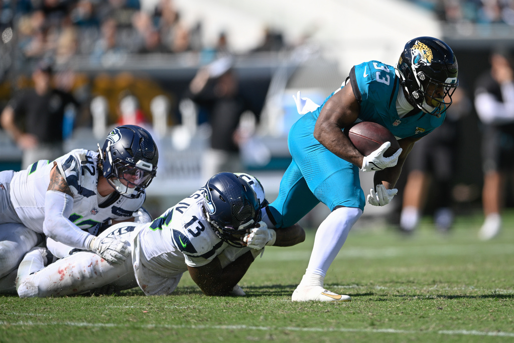 Jacksonville Jaguars running back Bhayshul Tuten (33) is tackled by Seattle Seahawks linebacker Ernest Jones IV (13) after a catch during the second half of an NFL football game Sunday, Oct. 12 2025, in Jacksonville, Fla. (AP Photo/Phelan M. Ebenhack)