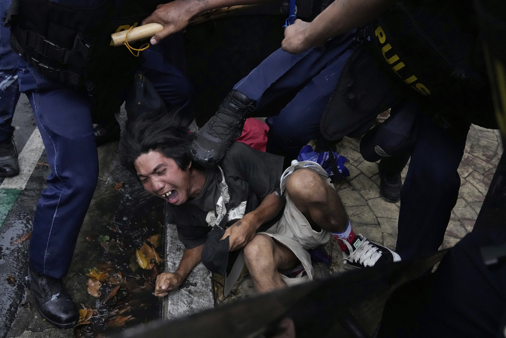 A protester reacts as he is kicked by police as he is arrested after clashes as they tried to enter the Malacanang presidential palace compound in Manila, Philippines on Sunday, Sept. 21, 2025. (AP Photo/Aaron Favila)