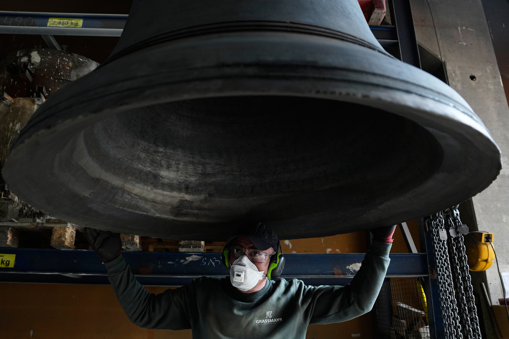 An employee inspects a bell at the 400-year-old family-owned bell foundry Grassmayr in Innsbruck, Austria, Friday, July 17, 2026. (AP Photo/Matthias Schrader)