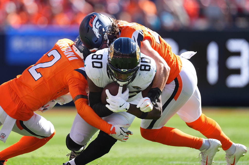 Jacksonville Jaguars tight end Quintin Morris (80) is stopped by Denver Broncos defenders Pat Surtain II (2) and Alex Singleton, right, in the first half of an NFL football game in Denver, Sunday, Sept. 20, 2026. (AP Photo/David Zalubowski)