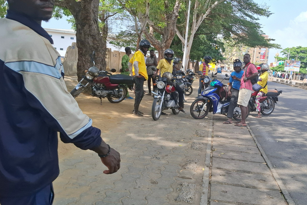 People gather near a roadway amid an attempted coup in Cotonou, Benin, Sunday Dec. 7, 2025. (AP Photo)
