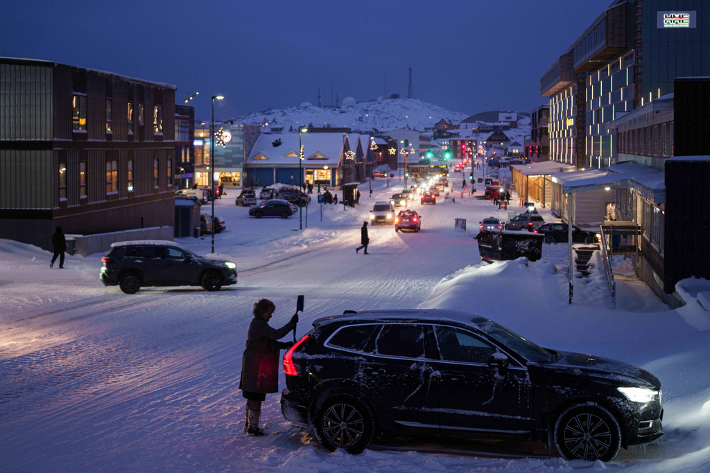 A woman cleans her car from snow in Nuuk, Greenland, on Monday, Jan. 12, 2026. (AP Photo/Evgeniy Maloletka)