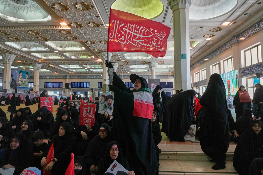 A woman holds a religious flag as mourners gather to commemorate the late Supreme Leader Ali Khamenei at the Imam Khomeini Mosalla Grand Mosque in Tehran, Iran, Tuesday, July 14, 2026. (AP Photo/Vahid Salemi)