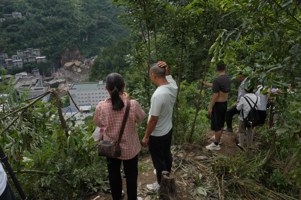 Residents watch as rescuers work at the site of a landslide in Pengshui County in southwestern China's Chongqing on Sunday, July 19, 2026. (AP Photo/Andy Wong)