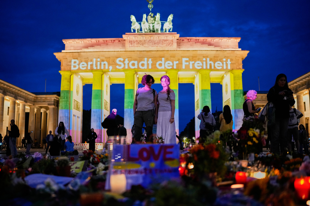People gather in front of the Brandenburg Gate illuminated with the message "Berlin, city of freedom", commemorating the victims, after a car rammed into a crowd at the Pride March in Berlin, Sunday, July 26, 2026. (AP Photo/Ebrahim Noroozi)