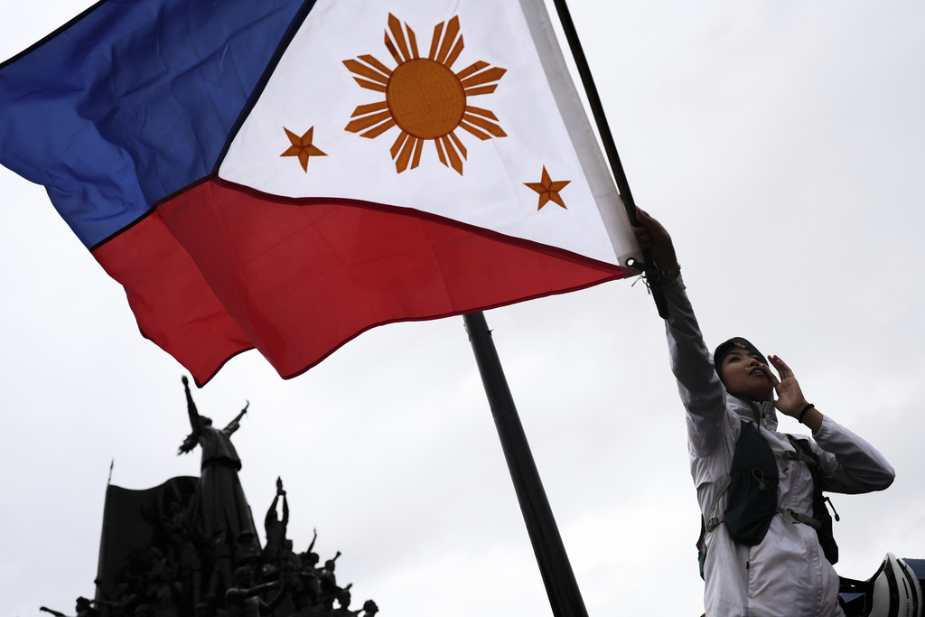 A woman waves a flag as thousands of protesters gather to rally against government corruption, in suburban Mandaluyong, east of Manila, Philippines, Sunday Sept. 21, 2025. (AP Photo/Basilio Sepe)