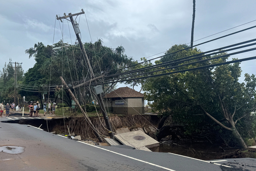 People gather near a collapsed road following severe storms on the island of Maui on Sunday, March 15, 2026, near the community of Weilea, Hawaii. (Athena Walsh via AP)