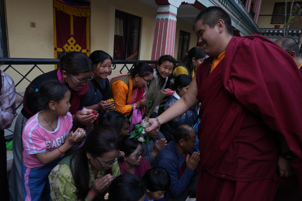 U.S.-born Buddhist lama Jalue Dorje smiles as he blesses people by tapping bowed heads with a ritual vase and a peacock feather at the end of 12 days of empowerments, or initiation rituals and teachings, bestowed by the abbot of Shechen Monastery in Kathmandu, Nepal, on Sunday, April 12, 2026. (AP Photo/Luis Andres Henao)