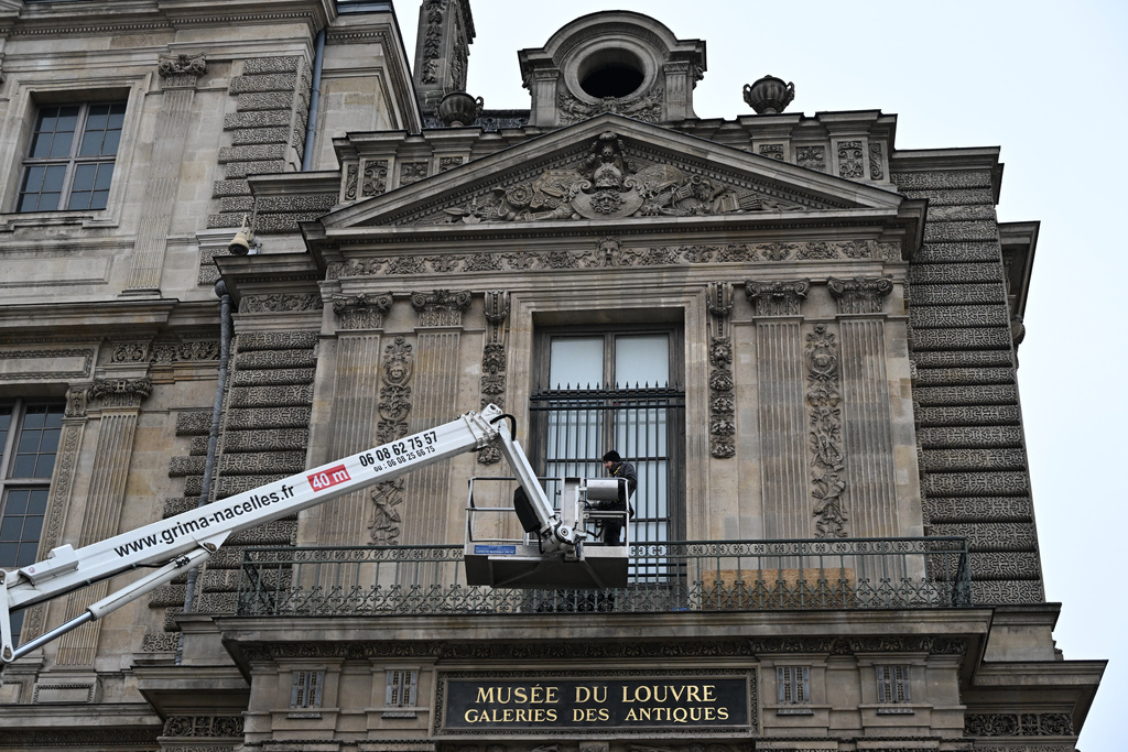Workers install metal security bars over the window where thieves broke into the Louvre museum on Oct.19, Tuesday Dec.23, 2025 in Paris. (AP Photo/Emma Da Silva)
