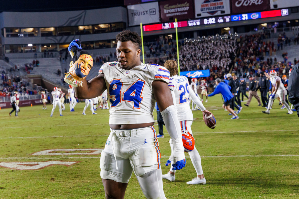 FILE -Florida edge Tyreak Sapp (94) holds a manikin head decorated like the Florida State mascot at midfield after his team defeated Florida State 31-11 in an NCAA college football game, Nov. 30, 2024, in Tallahassee, Fla. (AP Photo/Colin Hackley, File)