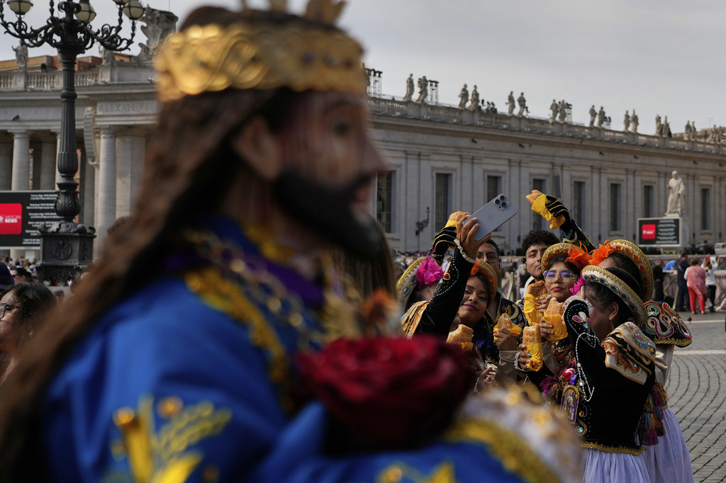 Faithful from Peru take selfie photos near a statue of Jesus Nazareno Cautivo de Monsefu, before Pope Leo XIV appears at his studio's window to bless the faithful gathered in St. Peter's Square at the Vatican for the Angelus prayer, Sunday, Sept. 14, 2025. (AP Photo/Gregorio Borgia)