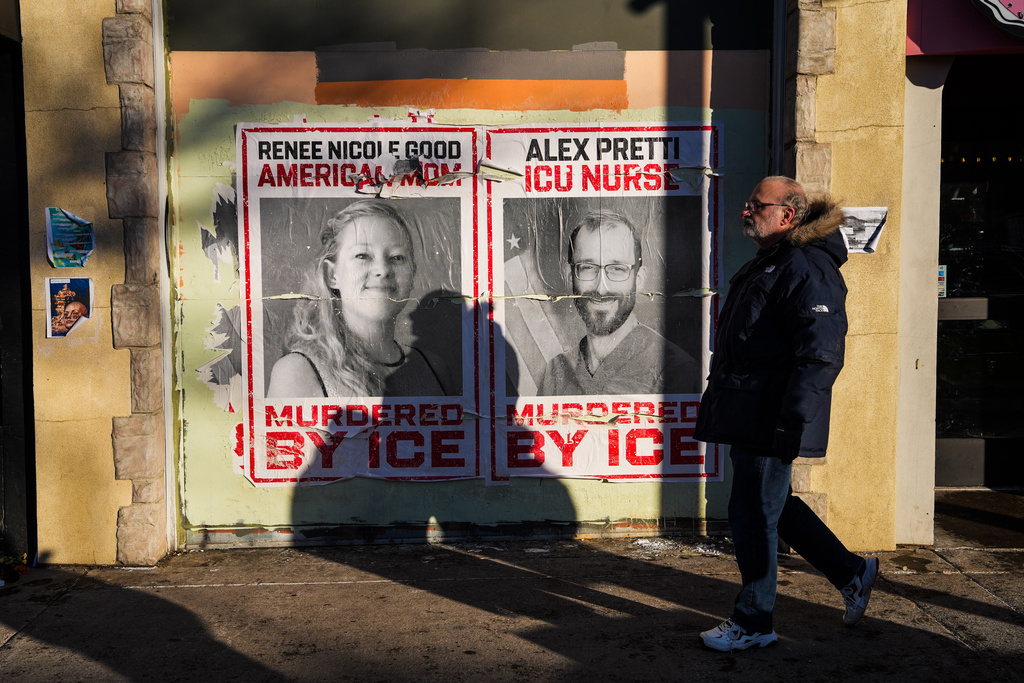 A man walks by posters of Renee Nicole Good and Alex Pretti, who were both fatally shot by federal agents, in Minneapolis, Saturday, Jan. 31, 2026. (AP Photo/Ryan Murphy)