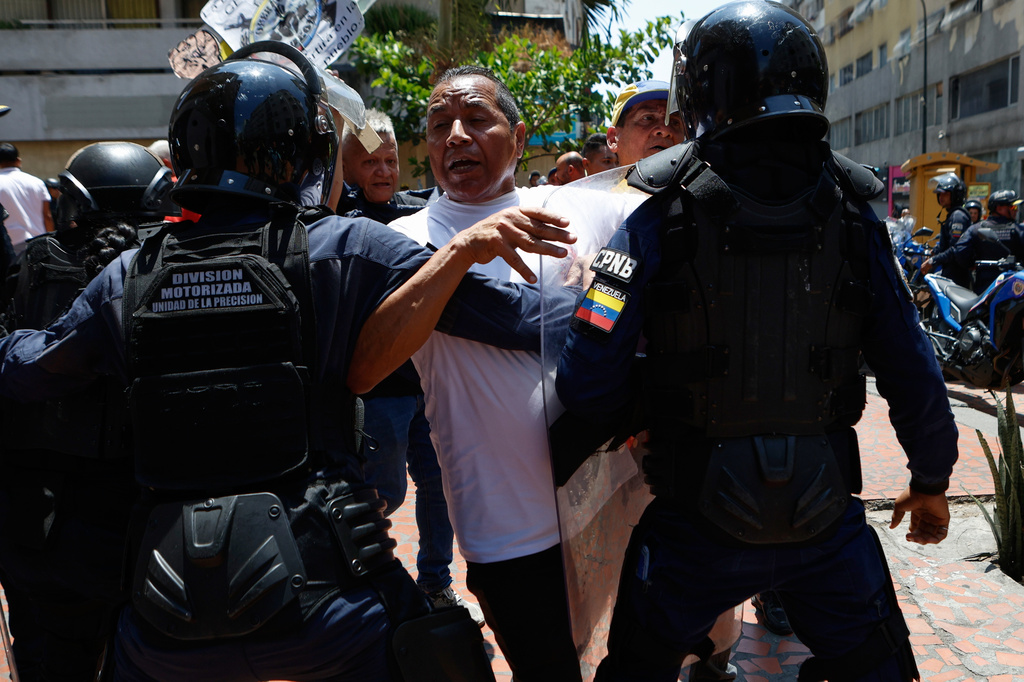 Bolivarian National Police stop protesters who are demanding higher salaries, pensions and benefits, from continuing their march to the Miraflores Presidential Palace in Caracas, Venezuela, Thursday, April 9, 2026. (AP Photo/Pedro Mattey)