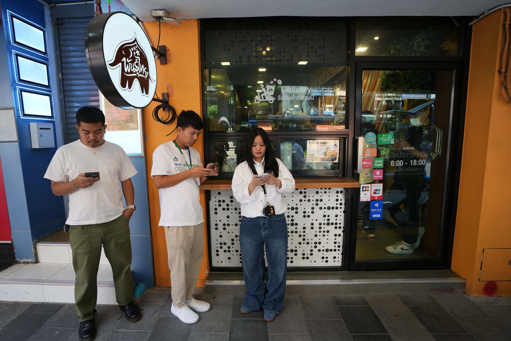 Customers wait for their coffee outside a coffee shop in Bangkok, Thailand, Wednesday, Feb. 11, 2026. (AP Photo/Sakchai Lalit)
