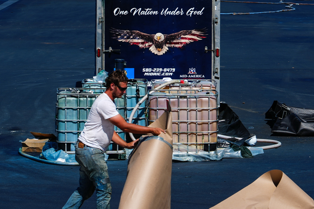 A worker clears paper from around the Lincoln Memorial Reflecting Pool after it was coated in a blue swimming pool surface ahead of the United States' 250th anniversary, Wednesday, June 3, 2026, in Washington. (AP Photo/Julia Demaree Nikhinson)