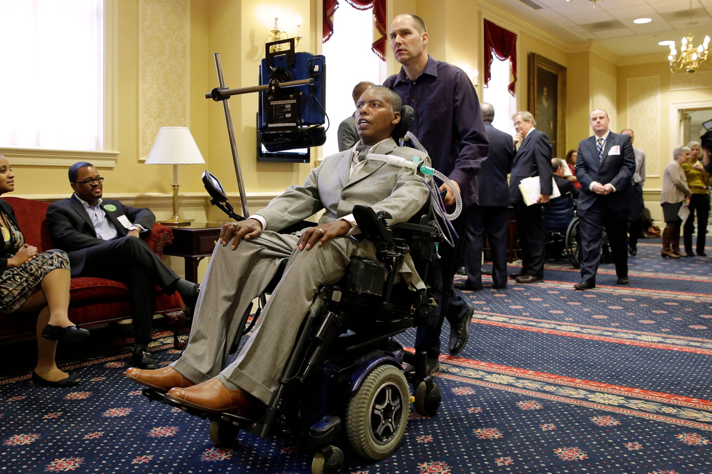 FILE - Former Baltimore Ravens NFL football player O.J. Brigance, center, current senior advisor to player development, is pushed by a nurse outside of a committee room in Annapolis, Md., March 10, 2015, after testifying to Maryland lawmakers against a right-to-die bill. (AP Photo/Patrick Semansky, File)