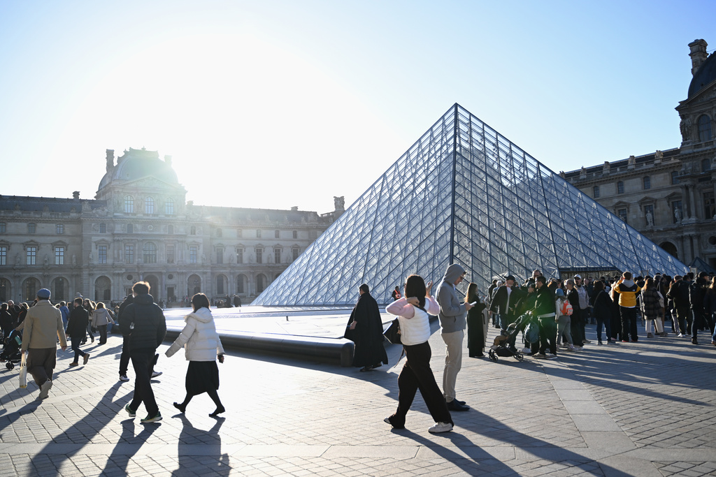 People wait for the opening of the Louvre museum, Thursday, Oct. 30, 2025 in Paris. (AP Photo/Emma Da Silva)