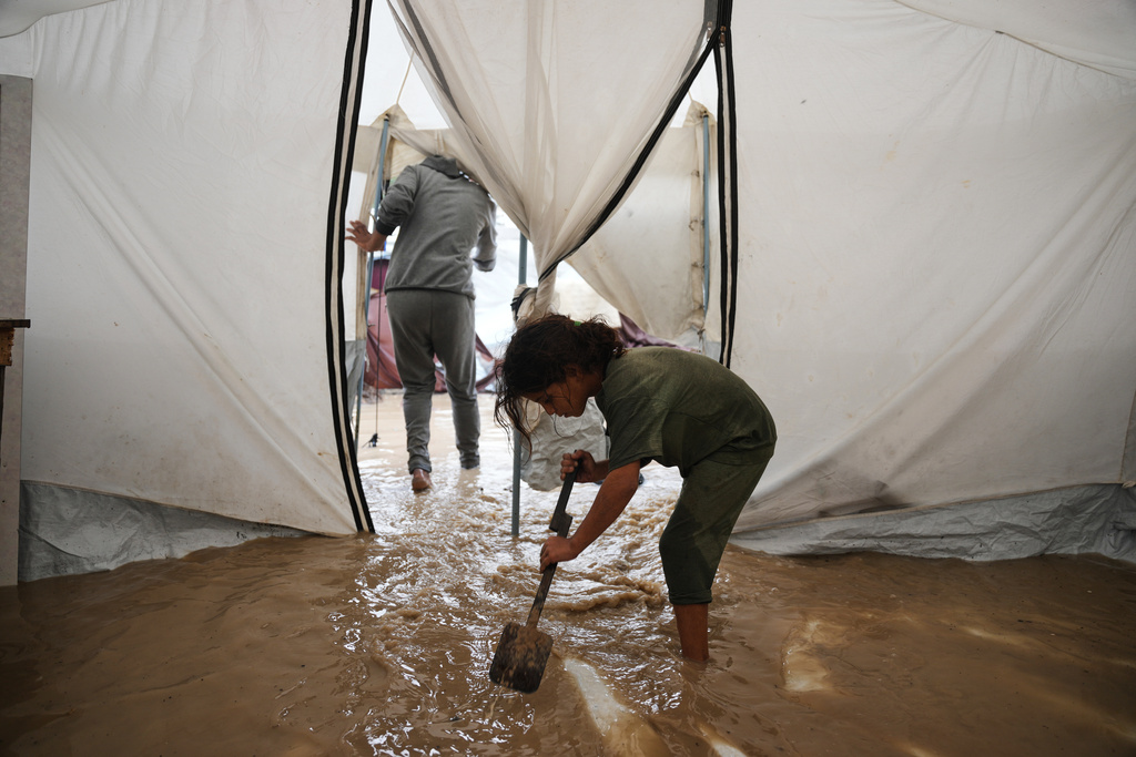 Saja Fayyad, 7, tries to clear water from her family's flooded tent at a temporary camp for displaced Palestinians after heavy rainfall in Deir al-Balah, central Gaza Strip, Tuesday, Nov. 25, 2025. (AP Photo/Abdel Kareem Hana)