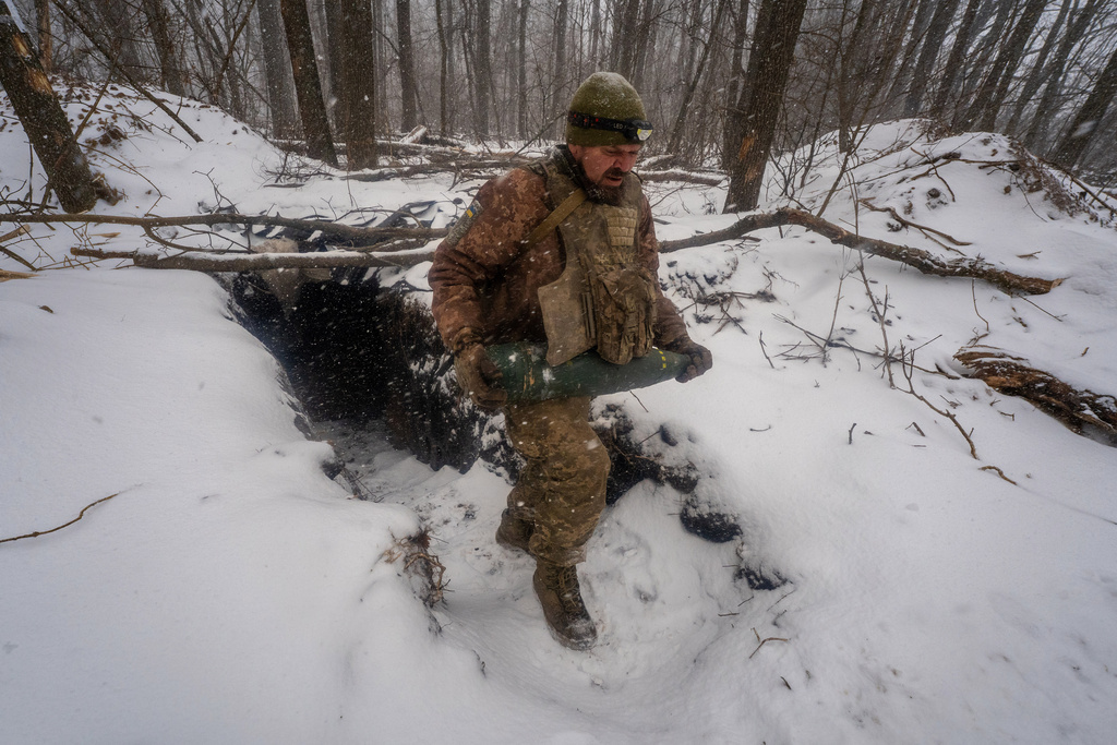 A Ukrainian serviceman of the 48th separate artillery brigade carries a shell as he prepares with comrades to fire towards Russian positions on the frontline in Kharkiv region, Ukraine, Wednesday, Feb. 18, 2026. (AP Photo/Andrii Marienko)