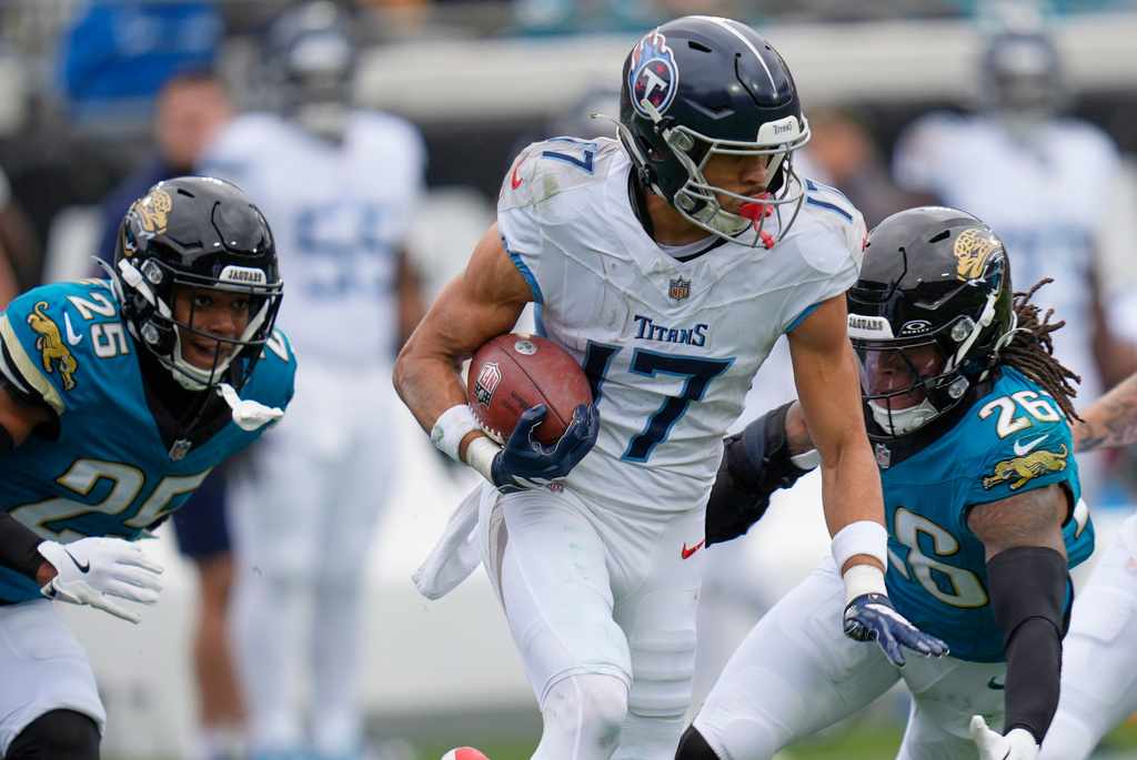 Tennessee Titans wide receiver Chimere Dike (17) returns a punt against Jacksonville Jaguars safeties Antonio Johnson (26) and Rayuan Lane III (25) during the first half of an NFL football game Sunday, Jan. 4, 2026, in Jacksonville, Fla. (AP Photo/John Raoux)