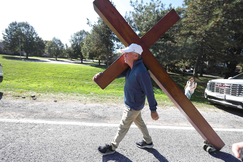 Dan Beazley carries his 10-foot-cross to the Church of Jesus Christ of Latter-day Saints, Monday, Sept. 29, 2025 in Grand Blanc Township, Mich. (AP Photo/Carlos Osorio)