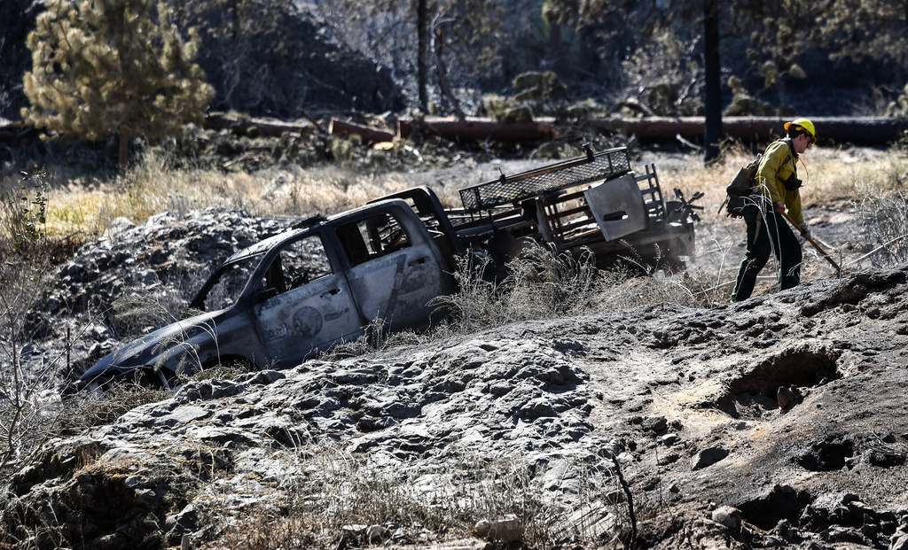 A firefighter works next to a firefighting rig that was destroyed in the Chelan Hills Fire on Wednesday, July 8, 2026, in Orondo, Wash. (Nick Wagner/The Seattle Times via AP)