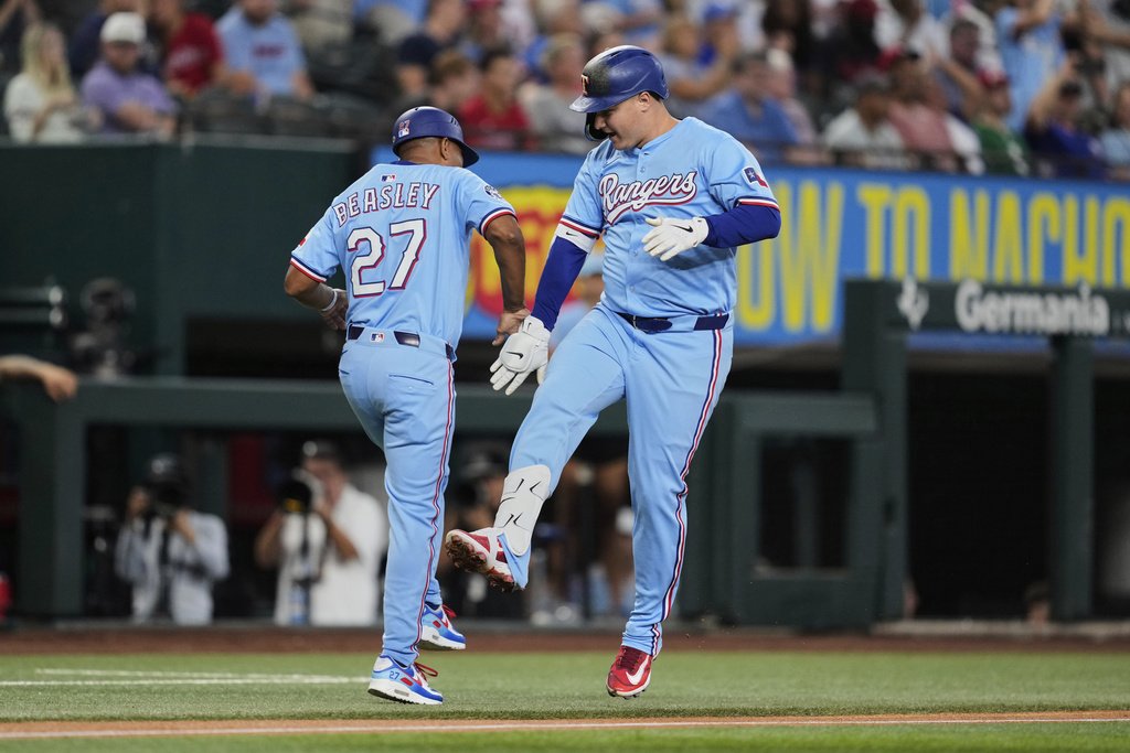 Texas Rangers third base coach Tony Beasley (27) and Joc Pederson, right, celebrate Pederson's two-run home run in the first inning of a baseball game against the Philadelphia Phillies Sunday, Aug. 10, 2025, in Arlington, Texas. (AP Photo/Tony Gutierrez)