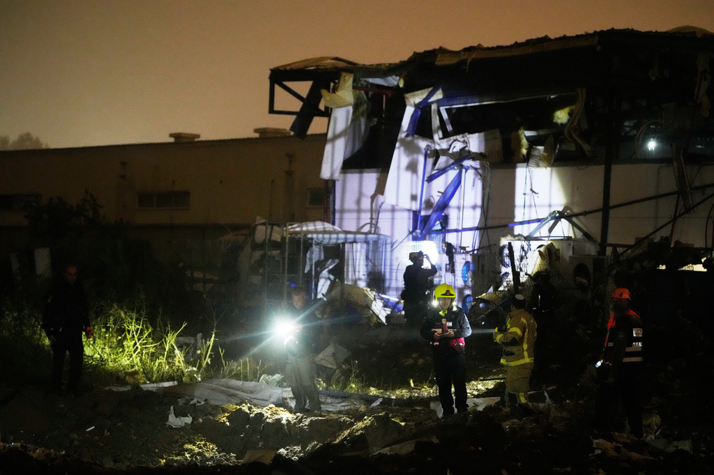 Israeli security forces and rescue teams inspect a site struck by an Iranian missile in Petah Tikva, Israel,Thursday, April 2, 2026. (AP Photo/Ohad Zwigenberg)