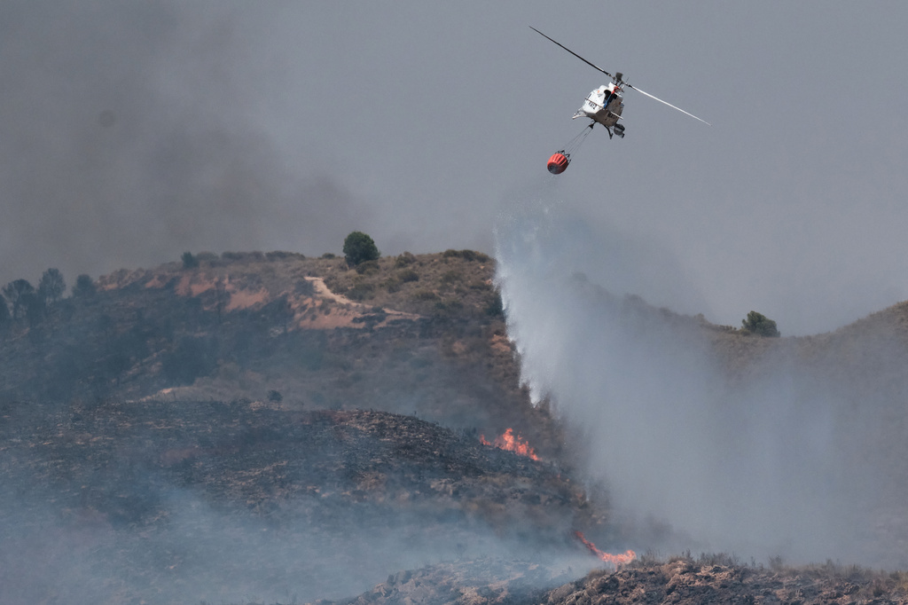 A helicopter drops water while fighting a wildfire near Los Gallardos, Almeria, Spain, Friday, July 10, 2026. (AP Photo/Gregorio Marrero)