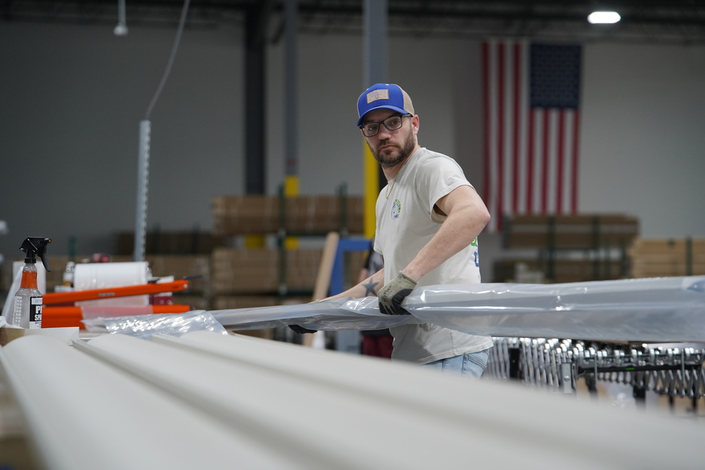 A worker lifts an aluminum beam on the factory floor at The Luxury Pergola, a company that manufactures aluminum pergolas, on Friday, Feb. 20, 2026, in Noblesville, Ind. (AP Photo/Obed Lamy)